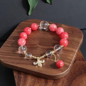 Detailaufnahme eines Armbands aus rosa Sonnenstein und klarem Kristall mit Bienenanhänger