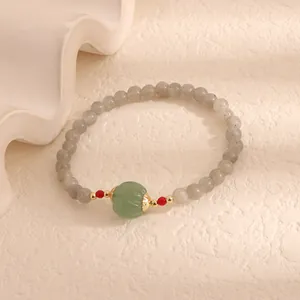 Close-up of moonstone beaded bracelet with a green carved pumpkin bead and red accents.