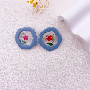 Detalle de pendientes hexagonales de resina azul con flores secas reales incrustadas