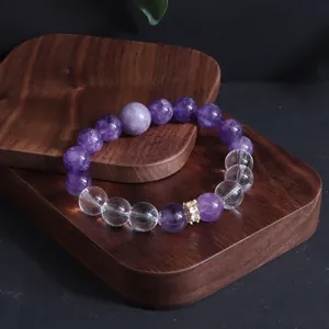 Nahaufnahme eines eleganten Armbands aus lila Amethyst und klarem Quarz auf Holzdisplay