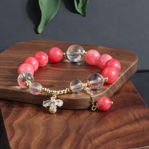 Detailansicht eines Armbands aus rosa Turmalinperlen mit einem Kristall-Bienen-Anhänger.