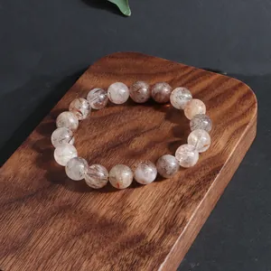 Vista detallada de una pulsera de cristal super 7 de oro negro sobre soporte de madera