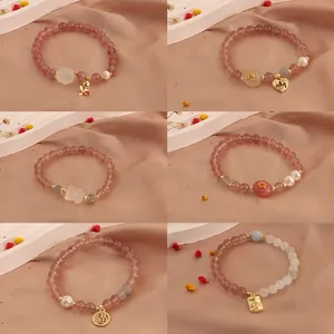 Various styles of strawberry quartz bracelets with moonstone and pearl charms on silk cloth