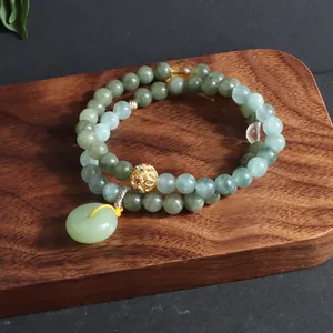 Nahaufnahme eines zweireihigen grünen Jade-Perlenarmbands mit Glücksbringer-Anhänger