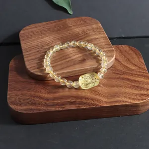 Close-up of natural citrine lemon quartz beaded bracelet with a fox charm on wood.