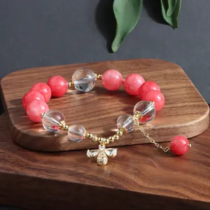 Detailansicht eines Armbands mit rosa und klaren Perlen, Gold-Biene-Anhänger und Kette