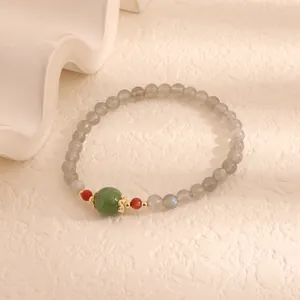 Detail view of a moonstone and green chalcedony beaded bracelet on a textured background