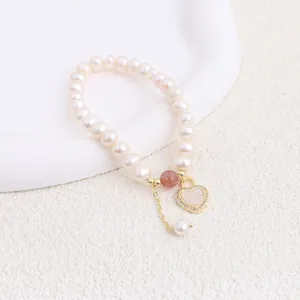 Detail view of a natural freshwater pearl bracelet featuring a gold heart pendant with shell inlay.