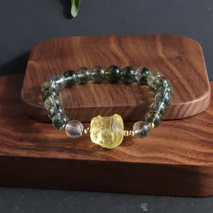 Detailed view of a green phantom quartz crystal bracelet featuring a yellow lion dance charm
