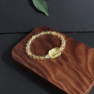 Close-up of natural yellow citrine crystal bracelet with carved fox charm on wood