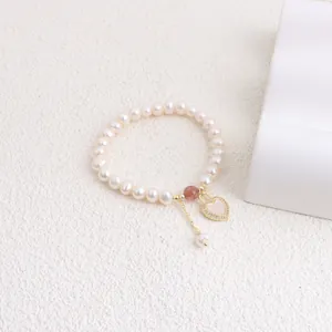 Close-up of freshwater pearl bracelet featuring a gold-framed heart shell pendant.