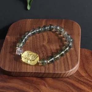 Detailed close-up of green phantom and lemon yellow crystal bracelet on a wooden tray