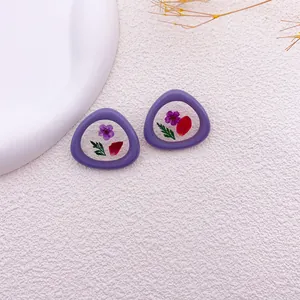Vista detallada de pendientes morados con flores secas reales en resina transparente