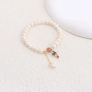 Close-up of elegant freshwater pearl bracelet with colorful zircon cross pendant