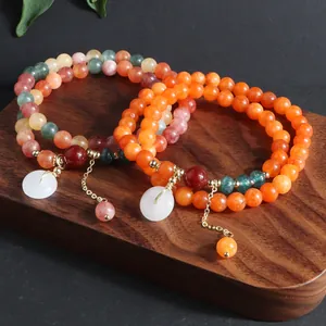 Detalle de pulseras de piedra natural multivuelta con dijes de jade Ping An Kou en madera.