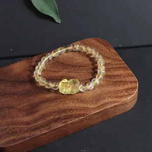 Macro view of natural citrine bracelet with carved pixiu charm on wooden display