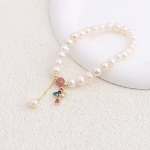Macro view of freshwater pearl bracelet with colorful zircon cross pendant detail