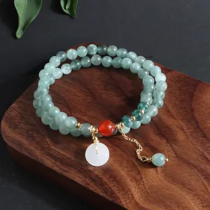 Detalle de pulsera multicapa de piedra natural con colgante blanco ping'an kou en base madera