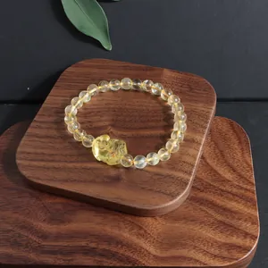 Natural citrine beaded bracelet with a carved crystal charm on a wooden display base