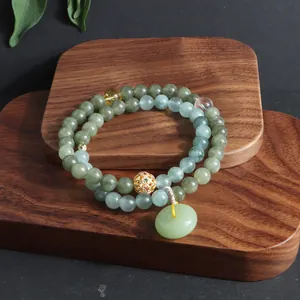 Zweischleifiges Jade- und Kristallarmband mit Ping-An-Kou-Anhänger auf Holzständer.