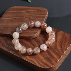 Detalle de una pulsera de cristal natural Super Seven sobre una base de madera
