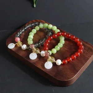 Makro-Detail von drei bunten Perlenarmbändern mit Achat und Perlen auf einem Holztablett.