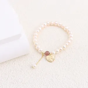 Close-up of elegant freshwater pearl bracelet with a gold heart charm and stone