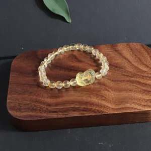 Natural yellow citrine crystal bracelet featuring a carved fox charm on a wood stand.