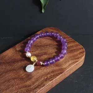 Makro-Detailansicht von Amethyst-Armband mit weißem Jade-Donut-Anhänger und Perle