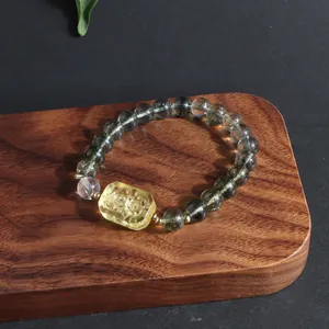 Macro view of Green Phantom and lemon-yellow crystal bracelet on a wooden texture