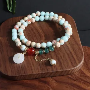 Detalle de pulsera de doble hilo de piedra natural con colgante de hebilla de paz blanca