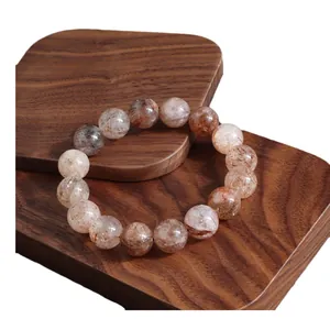 Pulsera de cuentas de cristal Super Seven oro negro natural sobre madera