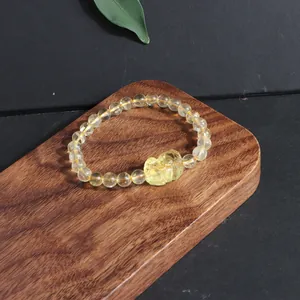 Detailed view of natural lemon citrine crystal beads with a carved fox charm on wood