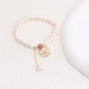 Macro detail of natural freshwater pearl bracelet featuring a sparkling zircon flower pendant.