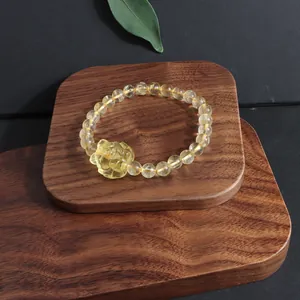 Detailed view of natural citrine bracelet with carved fox pendant on wooden base