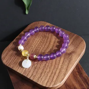 Nahaufnahme eines Amethyst-Armbandes mit weißem Jade-Anhänger und Perlen-Detail
