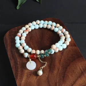 Detalle de una pulsera de varias vueltas de piedra natural con colgante Ping'an de jade blanco