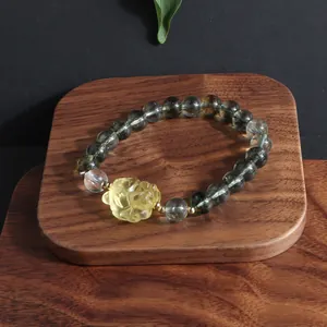 Detailed close-up of green phantom quartz bracelet with a yellow carved flower charm