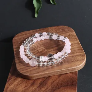 Close-up of double-strand natural crystal bracelet with pink and clear beads on wood tray