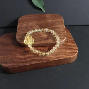 Detailed macro view of natural citrine crystal bracelet featuring a carved charm on wood