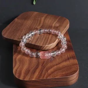 Gros plan détaillé d'un bracelet Pixiu en quartz fraise et cristal de roche sur socles en bois