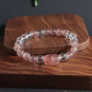 Gros plan sur un bracelet en quartz fraise et cristal de roche avec breloque Pixiu