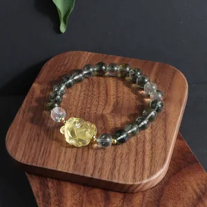Close-up of elegant green ghost quartz bracelet with yellow carved flower on wood base