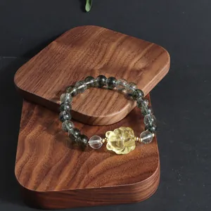 Detailed view of a green phantom quartz bracelet featuring a yellow carved lion plaque.