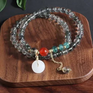 Vista detallada de una pulsera multicapa de piedra natural con colgante de jade blanco.