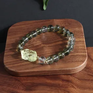 Macro view of green phantom and lemon yellow crystal bead bracelet on a wooden display tray