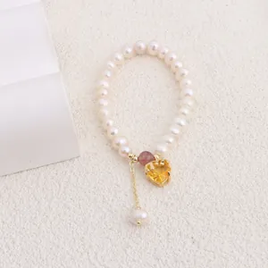 Close-up detail of a natural freshwater pearl bracelet featuring a yellow heart-shaped crystal pendant