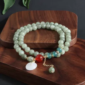 Detalle de una pulsera multicapa de piedra verde natural con colgante de jade blanco retro