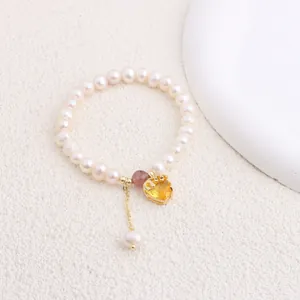 Macro view of natural freshwater pearl bracelet featuring a yellow heart gemstone pendant