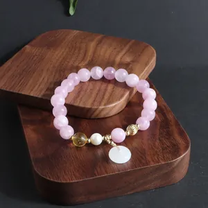 Detail eines Armbands aus rosa Kristallperlen mit weißem Jade-Anhänger und Perle